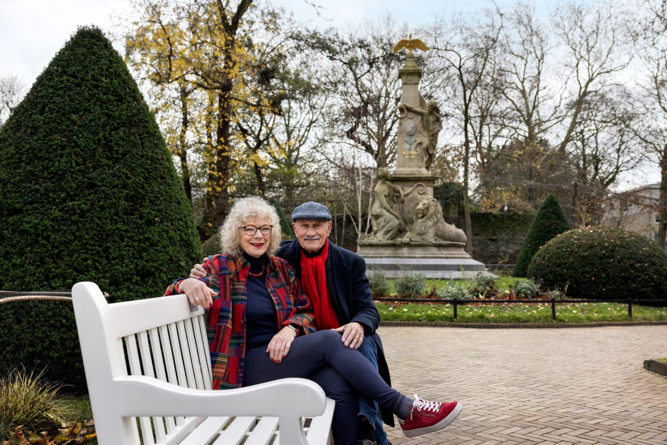 Mooi stel met rode accenten zitten samen op hun bankje in de Engelse tuin in Artis