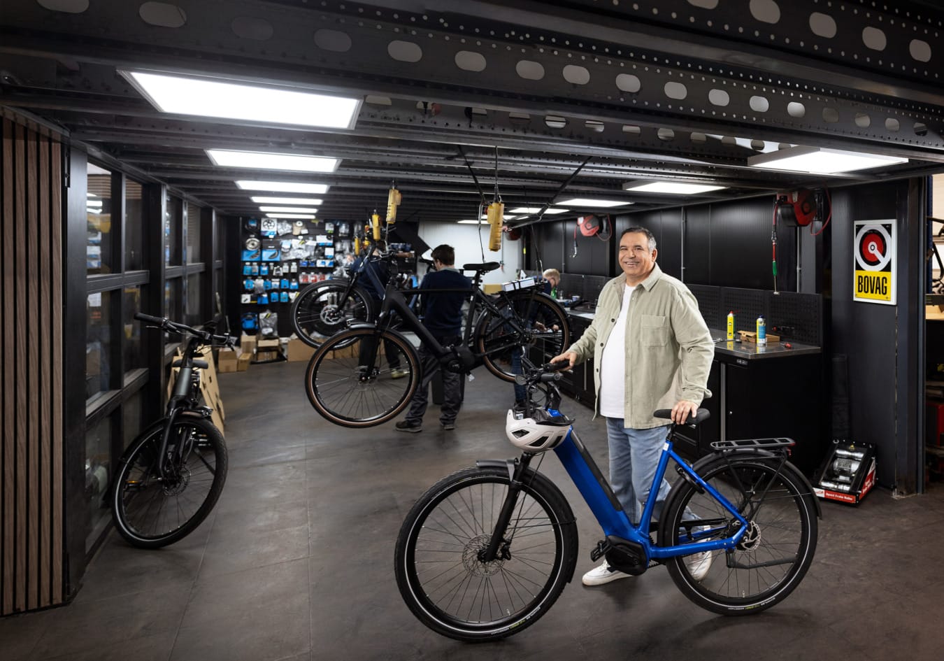 Model staat lachend bij elektrische fiets in fietsenwerkplaats voor campagne Vervoerregio