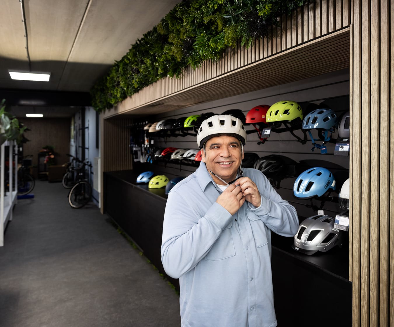 Lachende Arabische man past fietshelm in fietszaak voor veiligheid campagne Vervoerregio Amsterdam