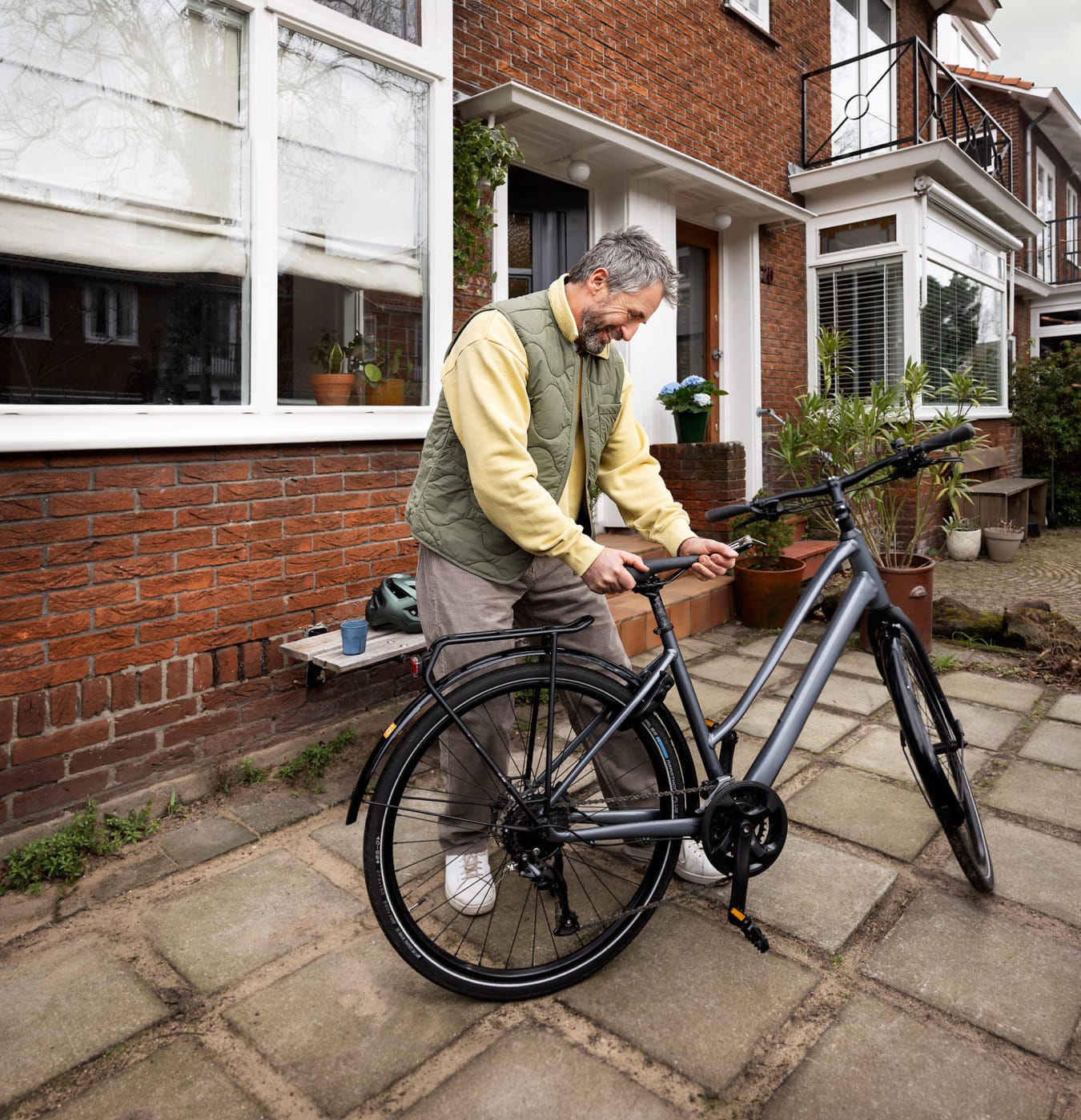 Blije man met baard checkt zijn fietszadel voor veiligheid campagne Vervoerregio Amsterdam