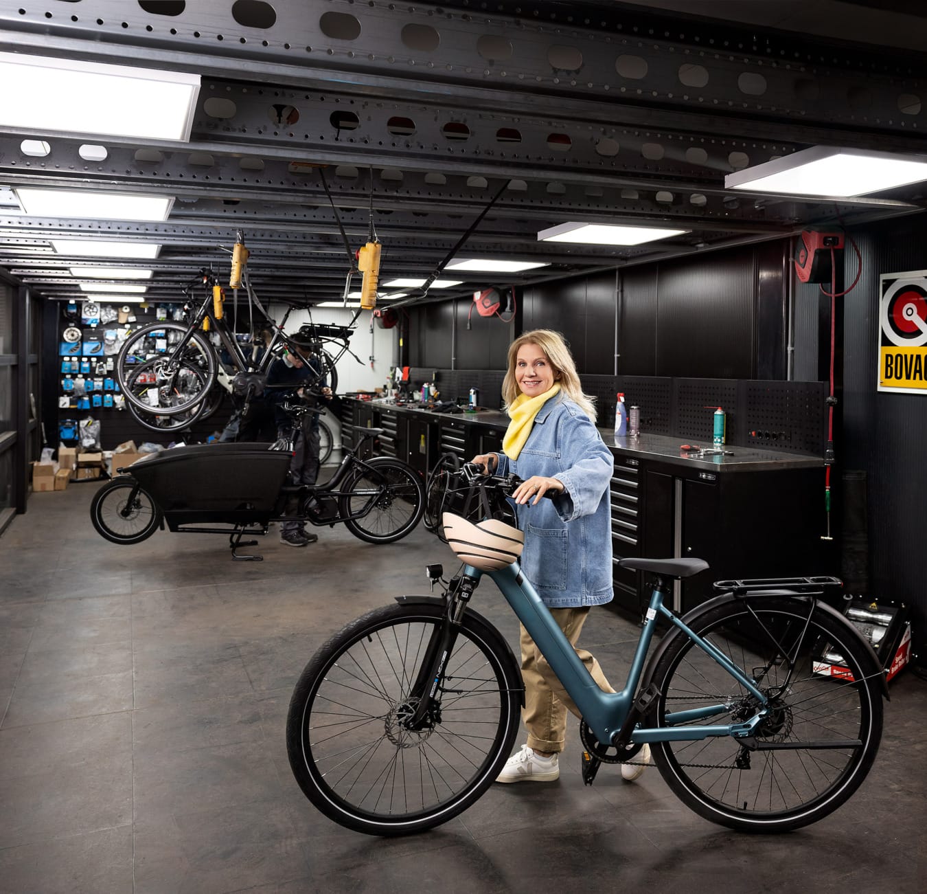 Model met fiets in de hand loopt in fietswerkplaats voor campagne Vervoerregio