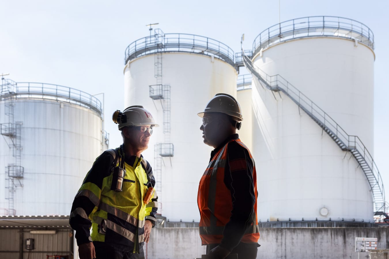 Twee mannen praten bij silo's