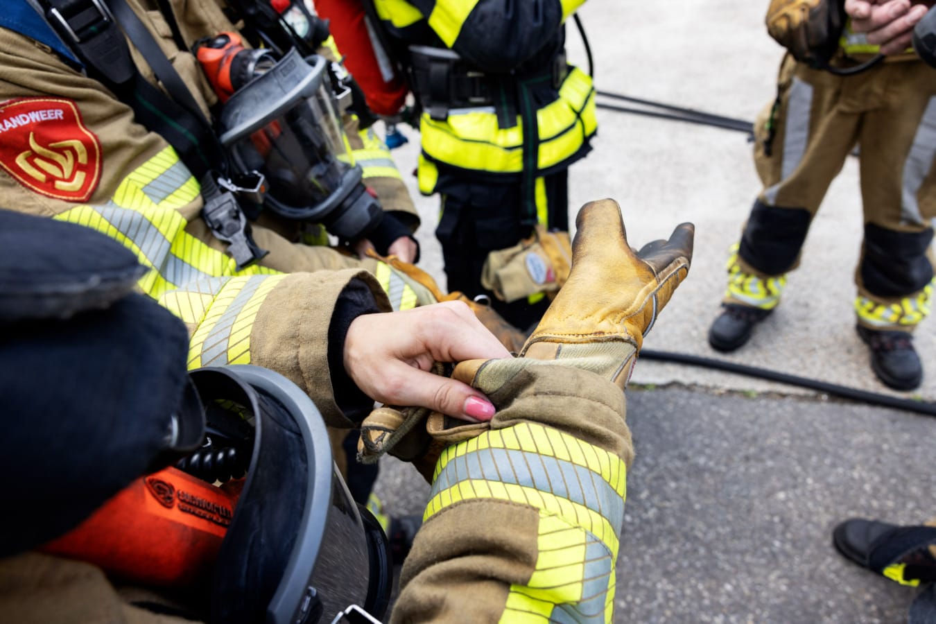 Brandweervrouw trekt handschoen aan, roze nagellak