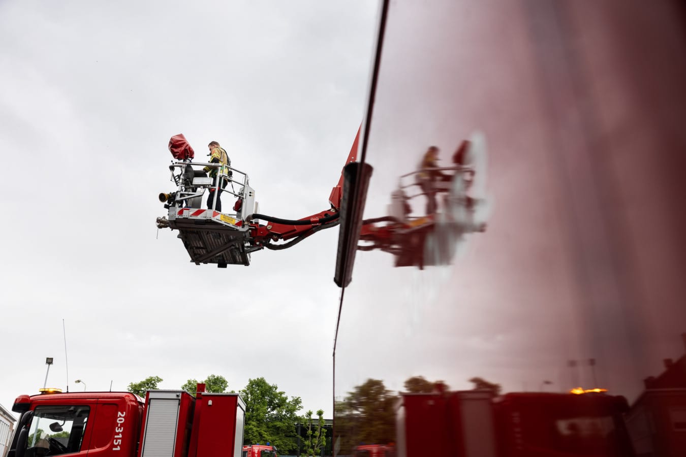 Brandweerman in hoogwerker, gespiegeld tegen brandweerauto