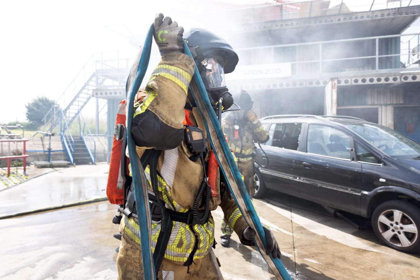 Brandweerman met brandslang over schouder