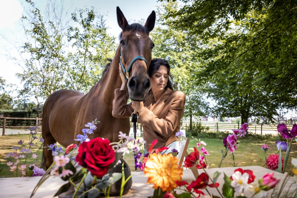 Vrouw met paard bij bloemen