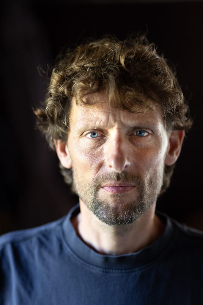 Man kijkt recht in camera, donkere omgeving, rauw
